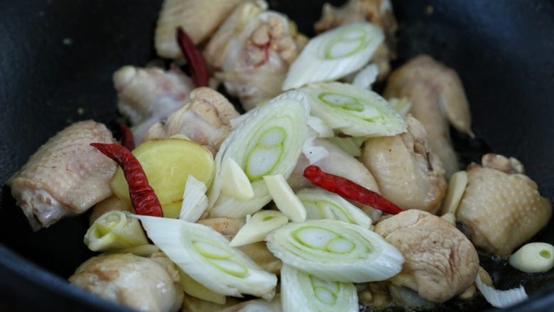 鸡翅腐竹烧土豆,然后放入葱花、姜片、蒜片和红干椒,翻炒出香味