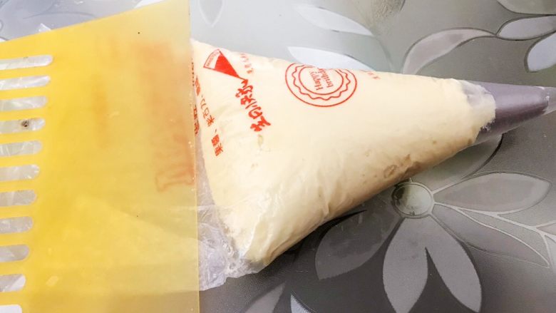酥酥的香草曲奇小花,裱花袋里装入曲奇花嘴,装入面糊用刮板推刮到最底部后,剪开裱花袋