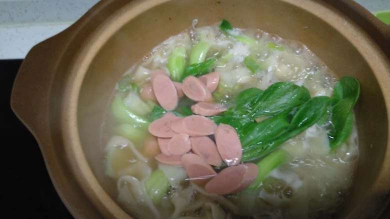 砂锅虾米手擀面,放入火腿肠煮一分钟,关火加入<a style='color:red;display:inline-block;' href='/shicai/ 756'>鸡精</a>、香油,搅拌均匀。