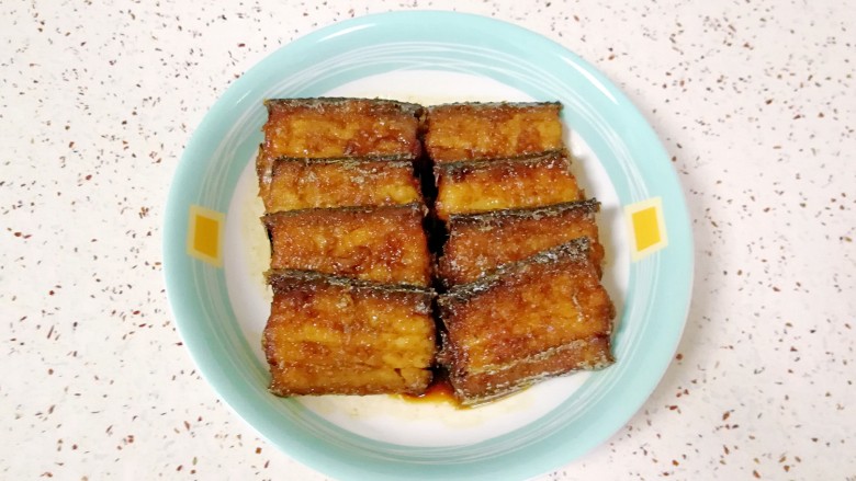 红烧带鱼,烧好的带鱼摆盘,锅内的汤汁去掉葱姜蒜和干红辣椒,浇在带鱼上面。
