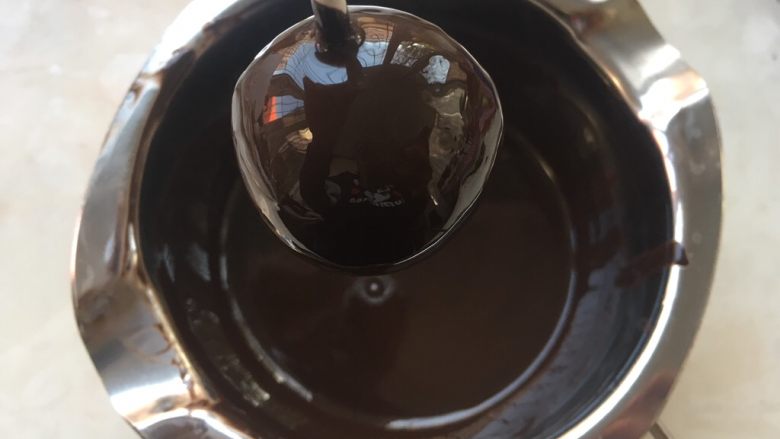 小魔鬼棒棒糖,滚好的蛋糕,要停放一会,让多余的巧克力滴下去,之后将巧克力擦在板子上,等待巧克力完全凝固