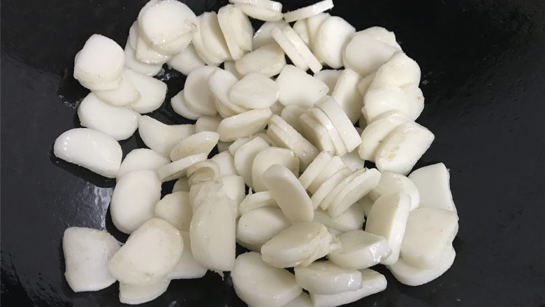 菠菜肉丝炒年糕,锅中倒入少许的油,放入切了片的年糕翻炒。