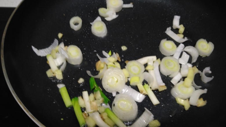 大虾炒米,锅中放入适量油,小火炒香葱、姜、蒜苗段。