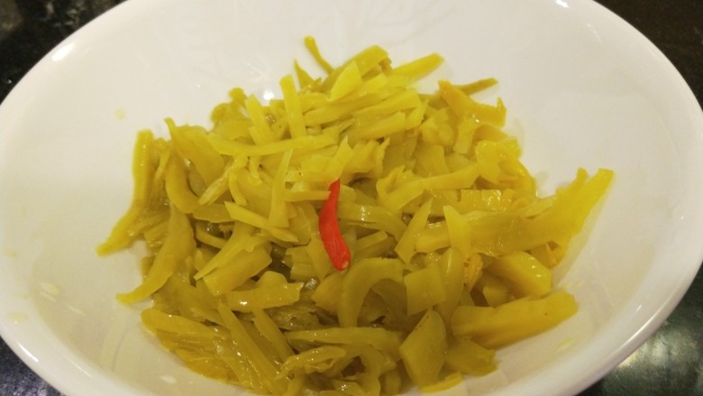 新文美食 酸菜红雕鱼,把酸菜切成丝,在倒回碗中。