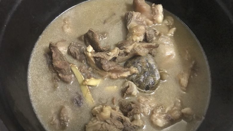 白萝卜炖牛筋巴脑,把在炖的牛筋巴脑转倒入铸铁锅中。盖上盖子,中火煮开,小火炖15分钟。