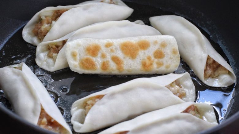 脆底猪肉洋葱锅贴,开小火煎至饼底呈焦黄色,淋入两汤匙清水盖上锅盖继续小火煎制