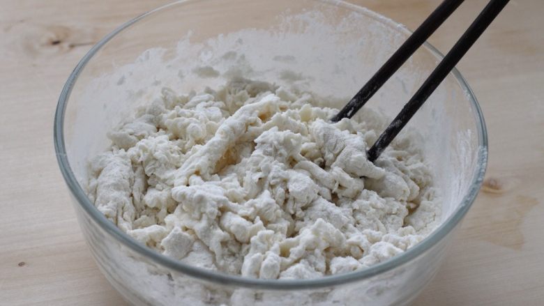 烫面豆沙饼,将面粉放入容器中,缓缓倒入热水,一边倒一边用筷子搅拌成棉絮状