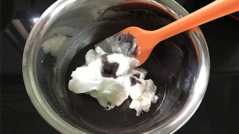 黑米戚风蛋糕,蛋白打好后,先取1/3的蛋白霜放入蛋黄糊中,番拌均匀。