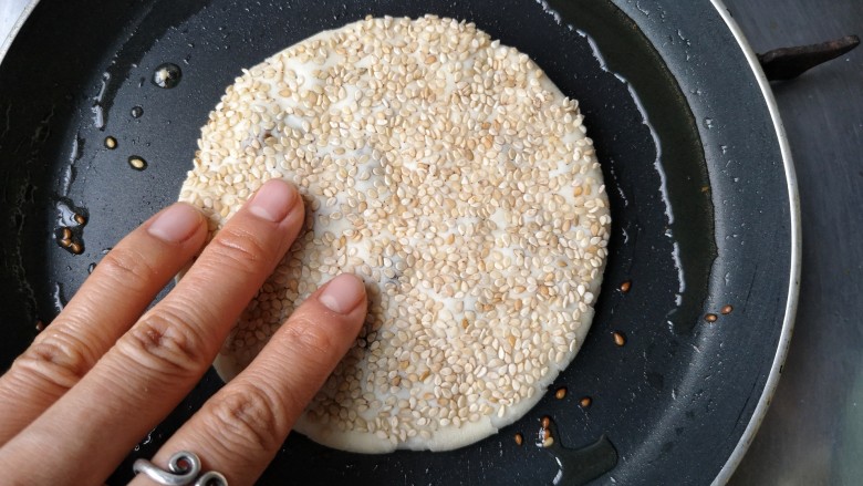 梅干菜肉烧饼,平底锅中适量油烧热,放入饼坯用手轻将边上向外压一压,中小火慢烙。