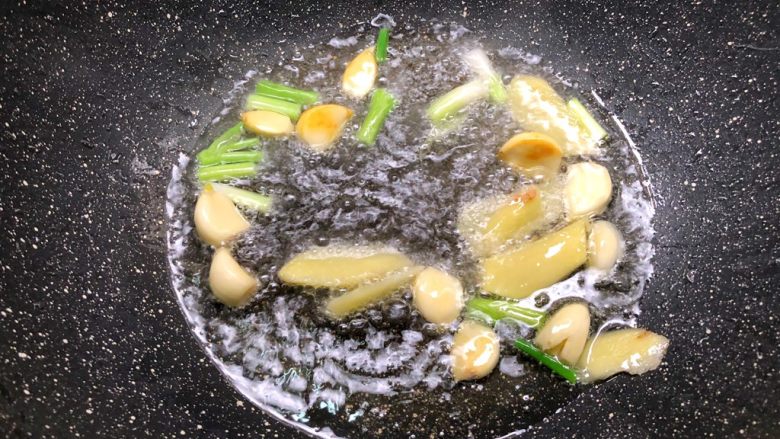 水煮肉片,热锅放入适量油,放入蒜瓣,葱白,姜片炒香。