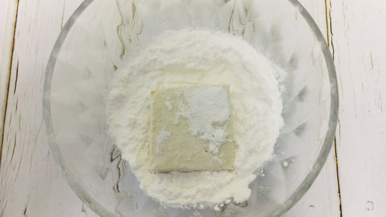 糖醋脆皮豆腐,清水洗净后的豆腐切成小块,沥干后裹上淀粉(包上淀粉煎出来的豆腐皮更加的酥脆好吃)放在盘子中。