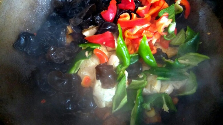 五花肉木耳炒豆腐,把木耳,豆腐,青红椒全部放入锅中翻炒