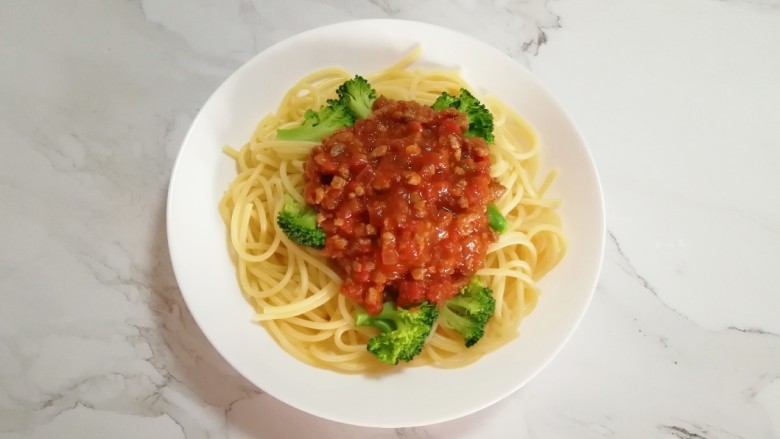 番茄肉酱意面,煮好的意面和西兰花一起盛在盘子里,浇上做好的肉酱。
