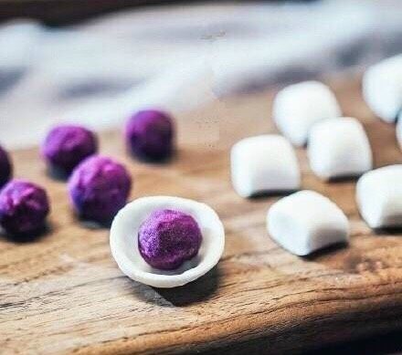 紫薯水晶汤圆,醒发好的木薯团子切成小块,并压成薄片包裹着紫色丸子搓圆(木薯约薄越显色)