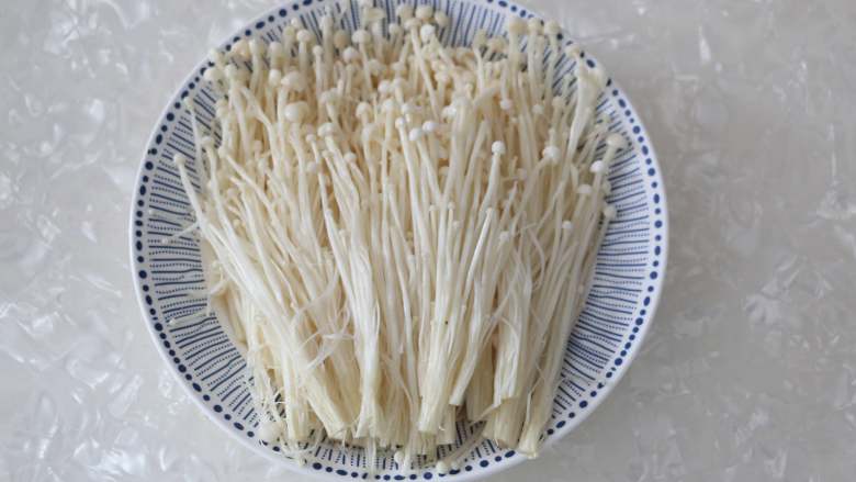 剁椒金针菇,金针菇沥干净水份,平铺在盘子中。这里最好用一个深盘,以防金针菇在烹制过程中出水溢出。