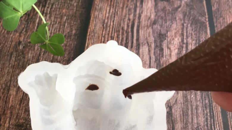 网红小狗慕斯蛋糕,在狗狗模具的眼睛和鼻子上挤上融化好的巧克力,然后放冰箱冷冻,冻硬
