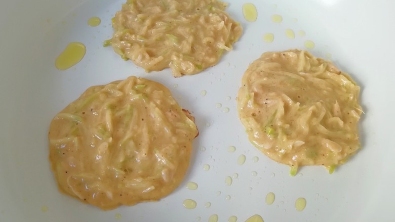 萝卜虾皮鸡蛋饼,平底锅刷上一层食用油烧热,用勺子舀一勺鸡蛋面糊倒入锅里摊圆,小火煎制。