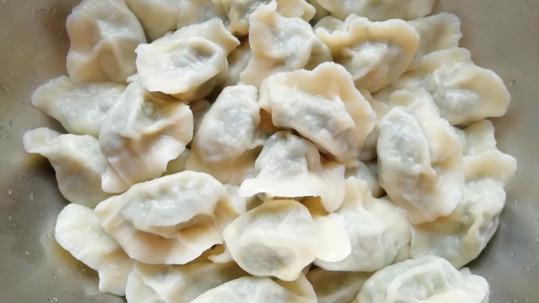 荠菜大肉馅饺子,饺子捞出来放在盆里,如果吃不完担心粘在一起,就放一点香油上下晃一下。