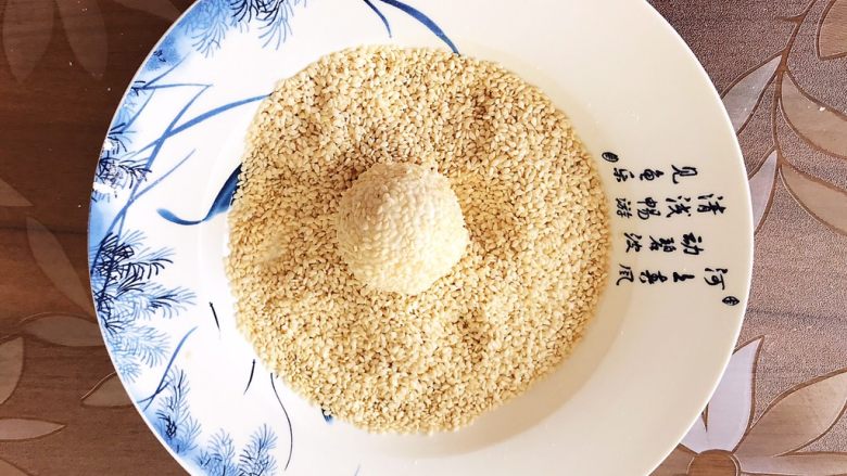 香炸麻团,再用手把表面的白芝麻压实,一个麻团生坯就包好了