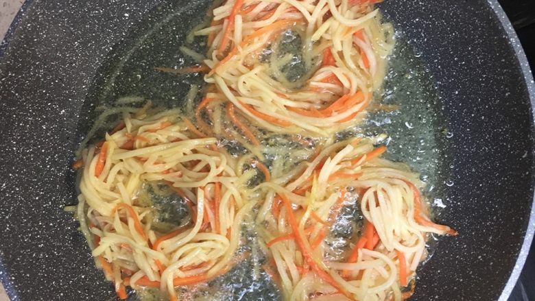 土豆丝(鸟巢)煎蛋,热锅加油,油在锅底铺上一层的量就好,将腌制好的土豆胡萝卜丝放入锅中,用筷子拨成圆形,中间空出放鸡蛋的位置