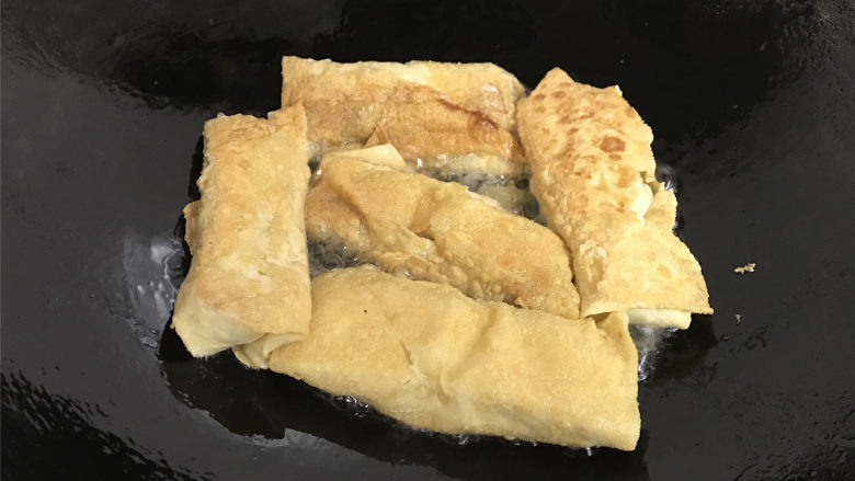 豆腐皮包肉,转中火,一面煎好后翻面再煎另一面,直至两面煎至金黄色。