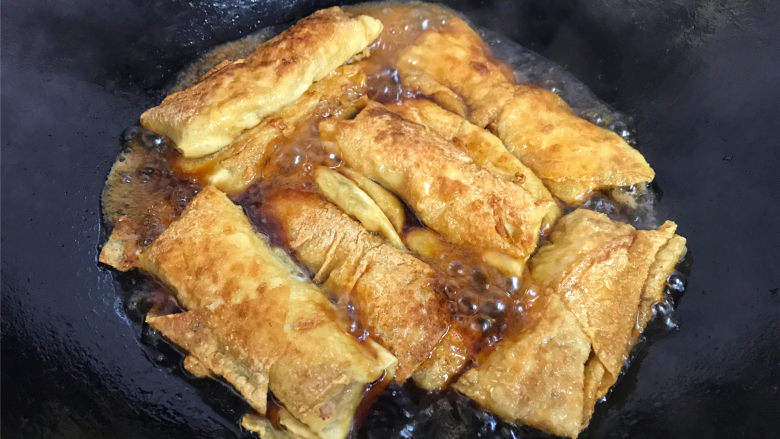 豆腐皮包肉,另取一锅,倒入适量水后加入生抽调味后把煎好的豆皮肉卷放入锅中。