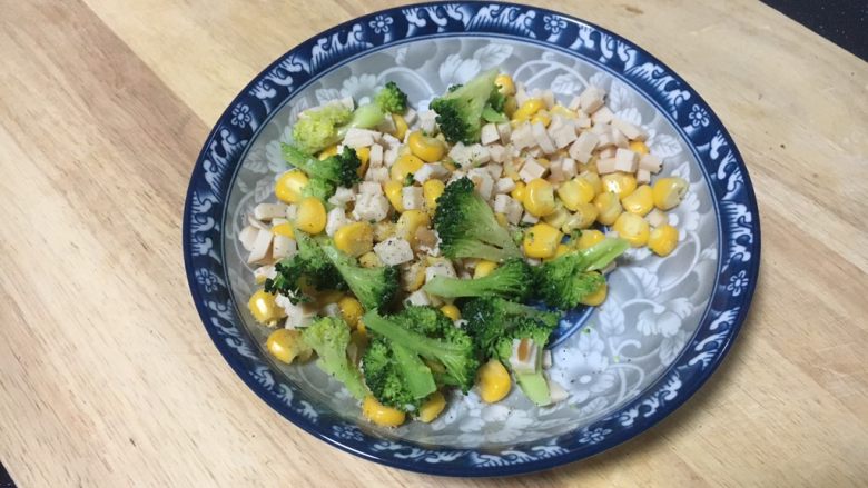 吐司披萨盏,将小朵西兰花、玉米粒、鸡肉火腿碎放在容器里,放入少许的盐和少许的黑胡椒碎,搅拌均匀备用。