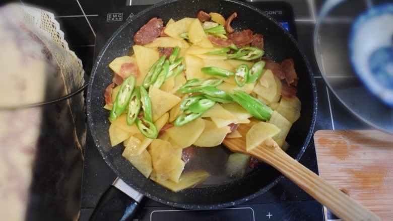 香肠土豆片盖浇饭,打开锅盖,收汁。待汁水快收干时,加入青椒,并加入适量的盐,翻炒均匀。