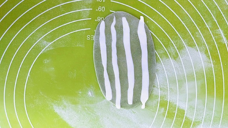 圣诞雪人馒头系列(一),绿色面团擀成薄片,白色面切成长条放在上面,用擀面杖继续擀平。