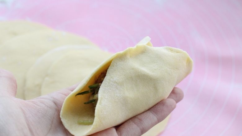 猪肉萝卜丝玉米面蒸饺,取一张饼皮用左手托住,在中间放适量馅料,然后将饼皮的中间对折捏严