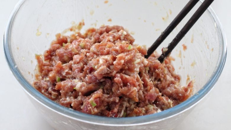 猪肉萝卜丝玉米面蒸饺,然后用筷子顺时针一个方向搅拌至肉馅上劲儿,这一步是为了使馅料抱团不散开,口感更好