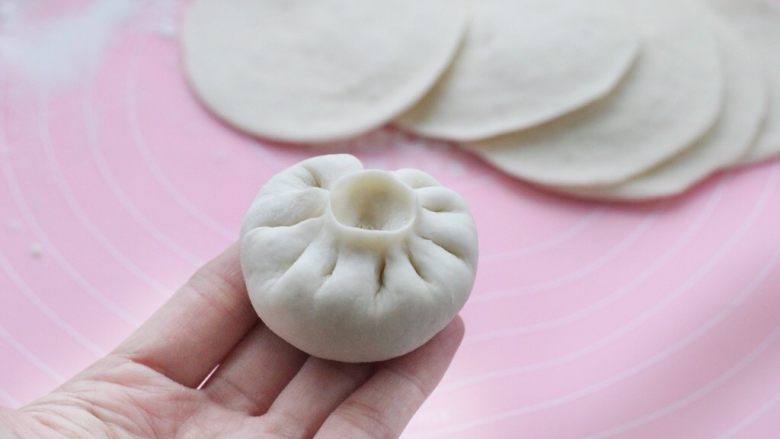 猪肉萝卜馅包子,取一个饼皮用左手托住,在中间放适量的馅料,用右手的拇指和食指捏出褶状,直至收口,一个包子就包好了