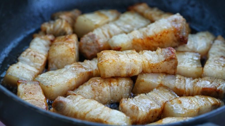 红烧肉炖萝卜,接着放入五花肉,翻炒至五花肉挂上糖色,肉的表面呈焦黄色