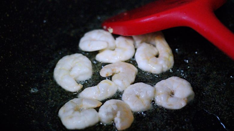 蒜薹鹅蛋虾仁炒饭,另起锅烧热后,把剩下的30克花生油烧热后倒入虾仁,小火慢慢进行翻炒。