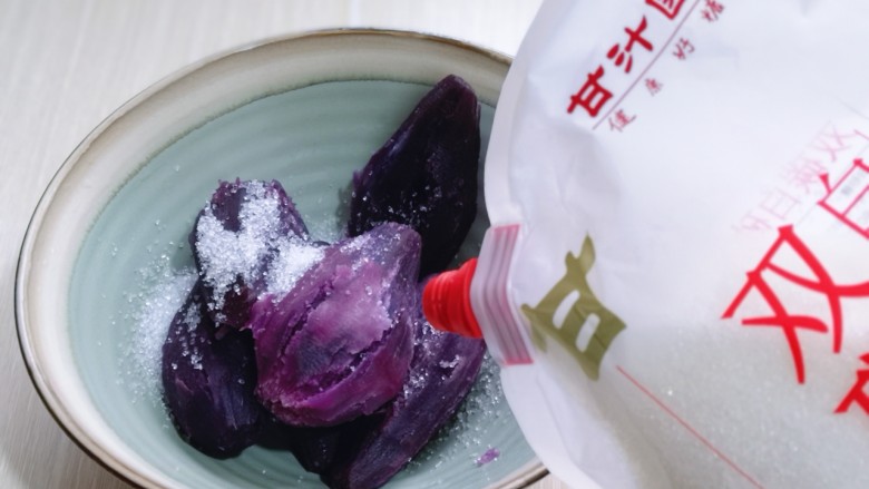 补血养颜~低脂紫薯红糖糯米饼,将蒸熟的紫薯放入器具中,加入白砂糖!