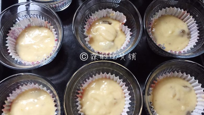香蕉葡萄干麦芬,舀入蛋糕纸托中,再放入模具中