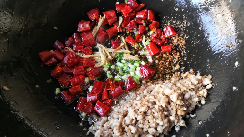 干煸芸豆,把炒好的肉末置于锅内一边,在锅底油处下入葱姜和干辣椒麻椒爆香。