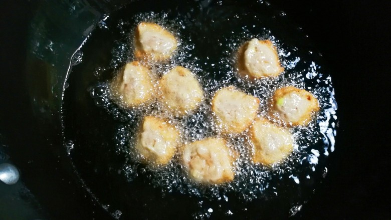 贴膘的肉圆,锅中放入适量食用油烧热,用勺子接住手中挤出的肉馅,一个一个放入油锅炸
