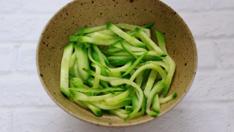 上汤干丝,取一个大一点的碗,把焯过水的黄瓜丝铺在底下。