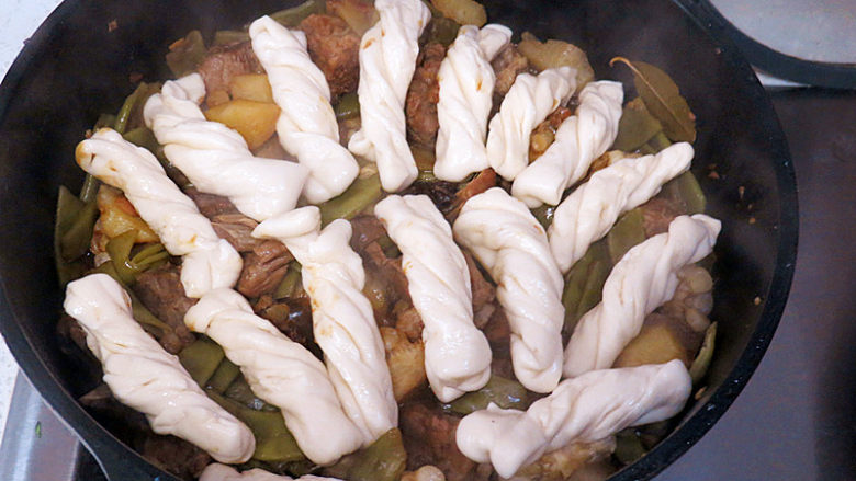 主食配菜一锅出【豆角排骨焖卷子】,30分钟后,菜炖好了,根据自己口味调整咸淡;再检查一下汤汁,如少的话可以加些开水。然后把卷子铺在菜的表面,盖好锅盖(注意焖卷子的时候最好不要再揭开锅盖了)
