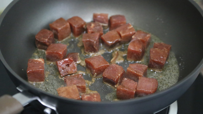秋葵黑椒牛肉,锅里倒入少许油,烧热后下牛肉粒翻炒煎制