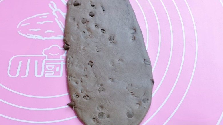 懒人必做~巧克力贝果,取一块醒发好的面团,用擀面杖擀成椭圆形。