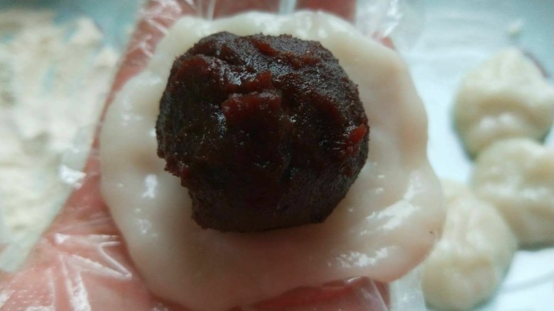 新文美食 成都豆沙糯米糍,把豆沙球放在糯米皮上包成长圆形。