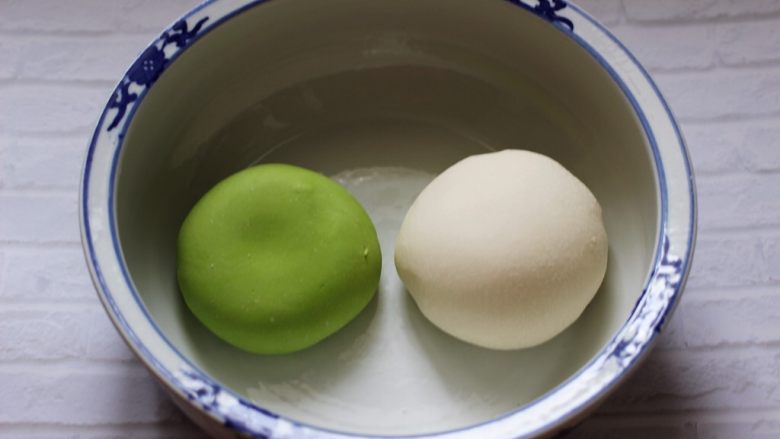 菠菜双色花样小馒头卷,和好的菠菜面团放入盆中,同样的方法把剩下的100克面粉和50克清水,1克酵母和10克甘汁园双碳白砂糖 加入面包机里和成白色的面团,把两块面团分别揉圆后进行醒发。