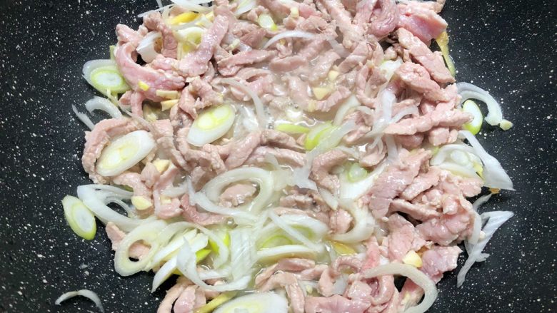 家常豆角焖面,煸炒至肉丝变色,放入大葱,姜丝,蒜末炒出香味。