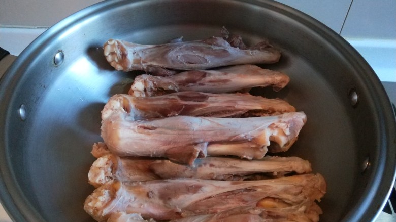 新文美食 红焖羊骨汤,把洗干净的羊腿骨码放皇后锅中。