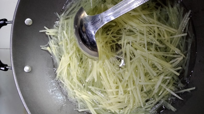 酸辣土豆丝,水烧开放入土豆丝焯水。焯好过后把土豆丝倒入过滤网,用凉水冲凉。