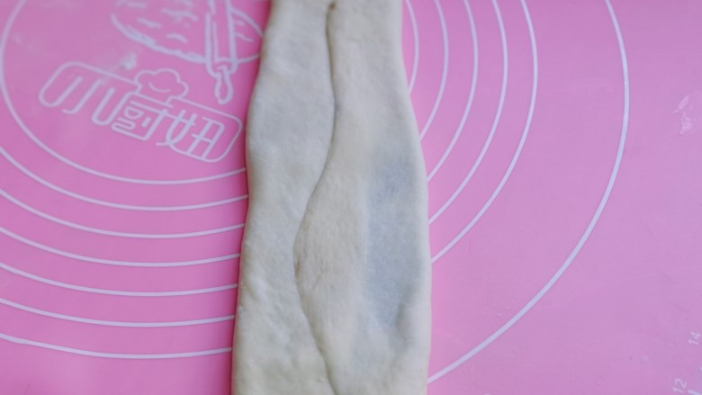 中种豆沙吐司面包,将擀好的长舌状两边向中间对折,用擀面杖轻轻擀长。