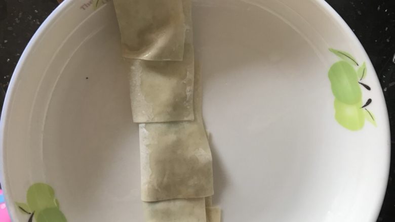 云吞皮葱油饼,将5块云吞皮铺平，然后抹油放葱，对折然后卷起来，压扁