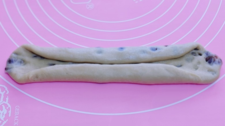 红豆日式咖啡面包卷,取一块面团,用擀面杖擀长舌状。